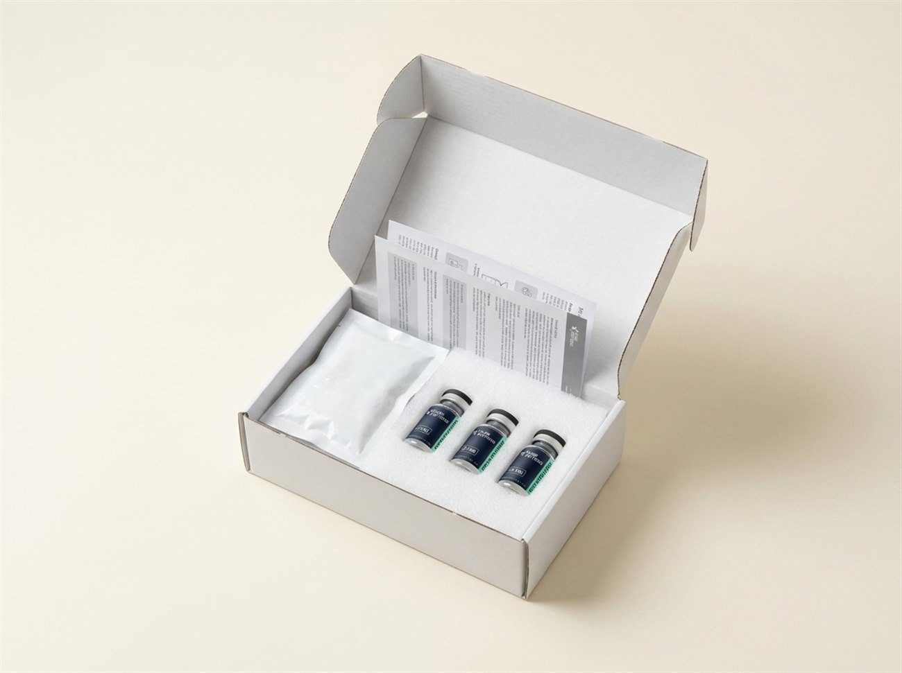 Plain unmarked shipping box opened, showing sealed vials, a gel ice pack and the printed certificate